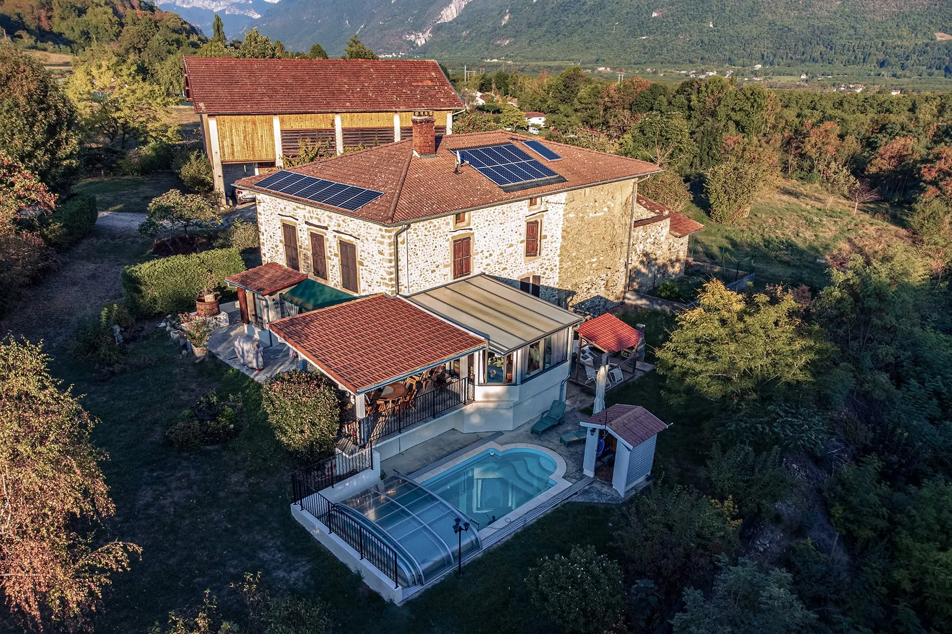Vue aérienne par drone d'une propriété en pierre avec piscine et panneaux solaires